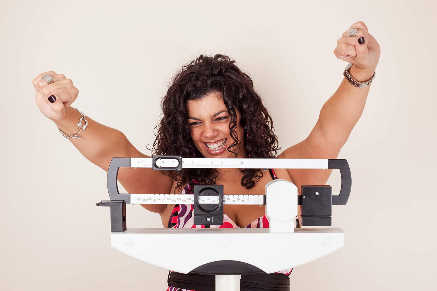 Happy woman celebrating her weight loss on a medical weight scale.