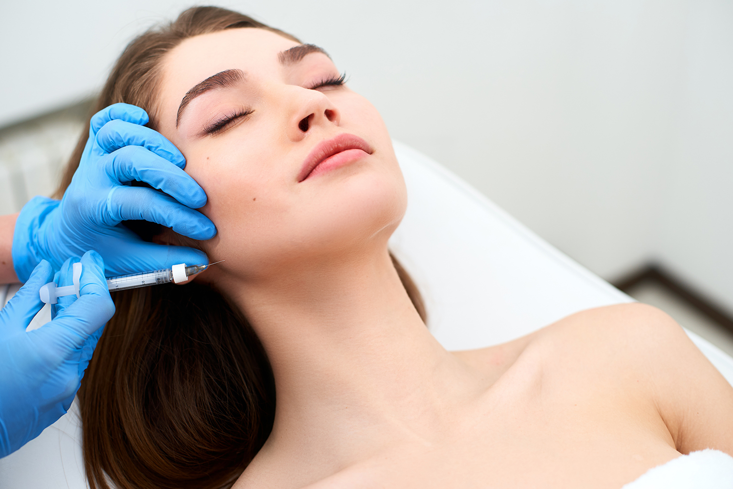 Side view of woman receiving microdermabrasion therapy on forehead at beauty spa. Hydrafacial procedure in Cosmetology clinic.