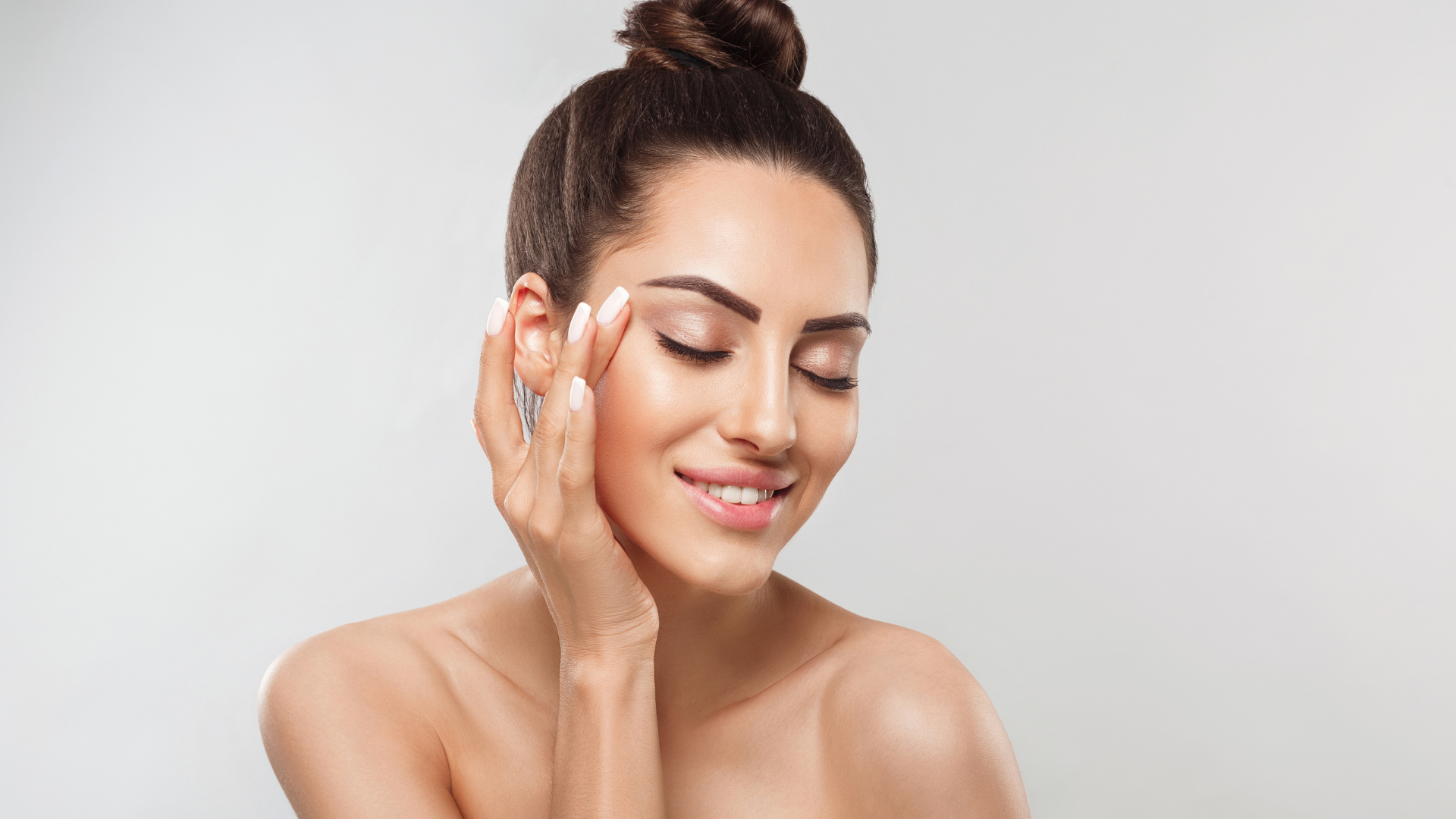 Attractive asian woman kissing a skincare product bottle. Female with best cosmetic product for skin.